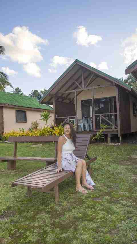 Girl sitting on sun chair with bungalow in the background