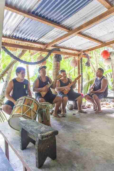 Crew playing music for guests over lunch buffet on island Moto Koromiri in Muri Rarotonga Cook Islands