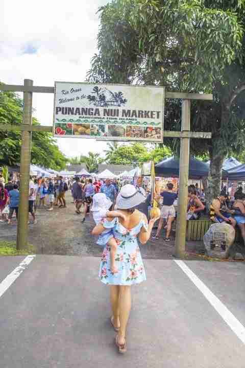 Mommy holding a coconut with toddler in her arm at Punanga Nui Market Rarotonga Cook Islands