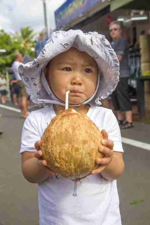 Toddler loving her coconut at the market