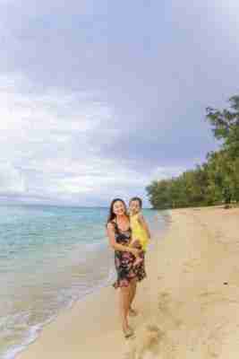 Mommy and daughter walking along the beach at The Rarotongan Beach Resort