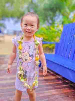 Toddler wearing her flower necklace in pyjama at the resort