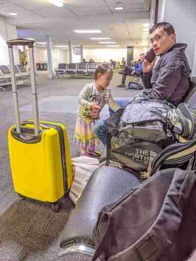 Toddler and Daddy sitting at the airport on the phone about flight cancellation compensation