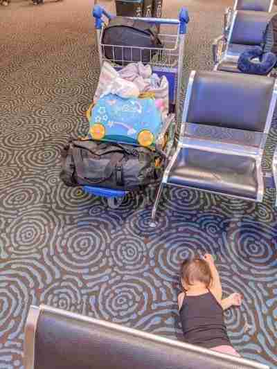 Toddler on the floor with a trolley of luggage after flight cancellation due to weather