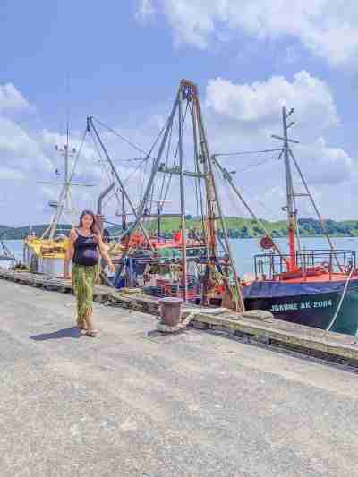Girl walking along wharf next to fishing boat