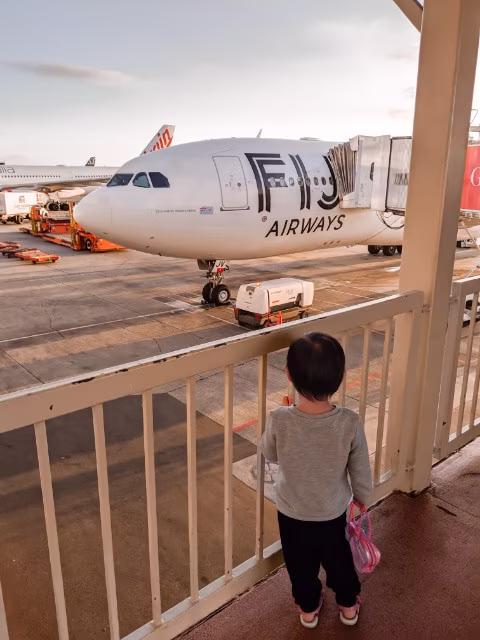 toddler looking out the window of Fiji Airway