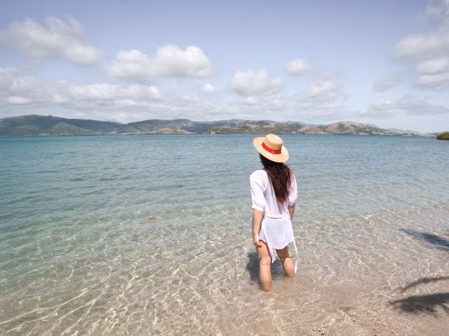 woman standing in the crystal clear turquoise water of Fiji remote island