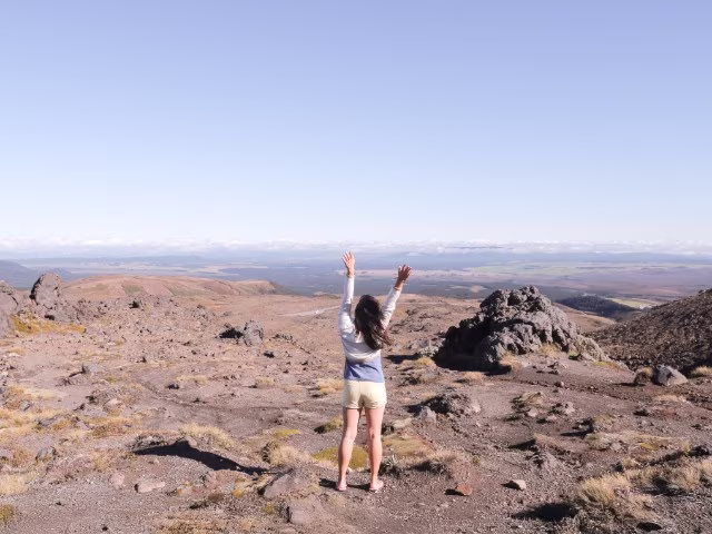 girl standing in rugged mountain with arms raised up embracing happiness