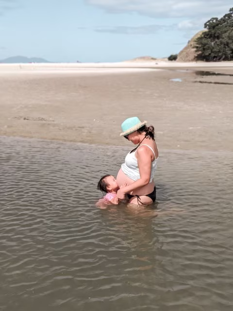 Letter To My Son Sister kissing baby boy bump on beach from mom