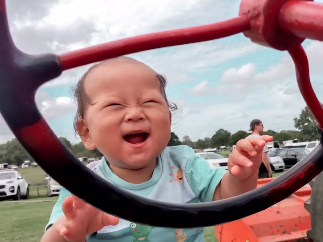 Happy excited baby sitting on big machine at The Kumeu Show