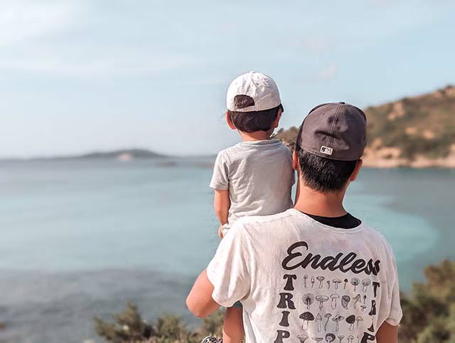 a candid moment of a family travelling around the world with their kids. The family, consisting of two adults and two children, are seen in a relaxed setting. The children are engaged in playful activities while the adults watch on, embodying the reality of family travel as opposed to the often idealised expectations. This image beautifully encapsulates the authenticity of their minimalist, family travel lifestyle.