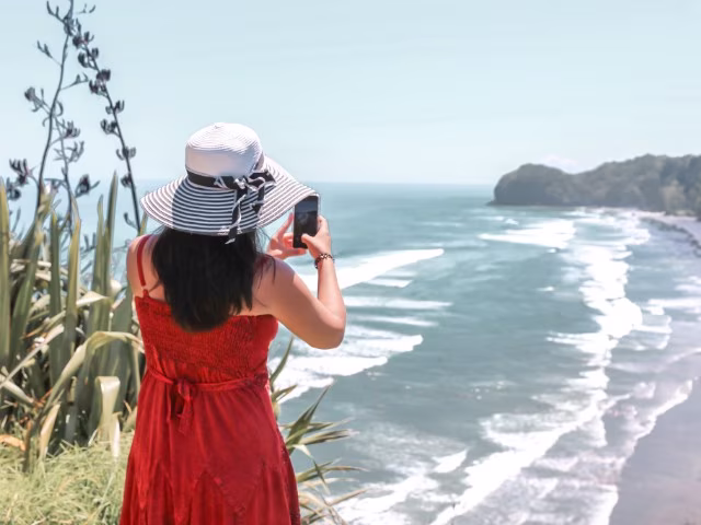 Taking photo on top of the hill with camera phone at Piha Beach in Auckland New Zealand