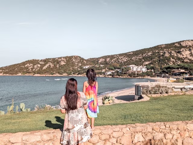 Mother daughter looking out to the sea in Baja Sardinia, Italy