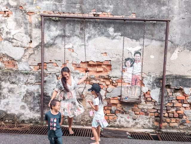 family woman girl boy posing in front of the mural wall in Penang, Malaysia