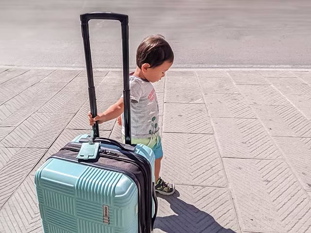 toddler helping to push a luggage