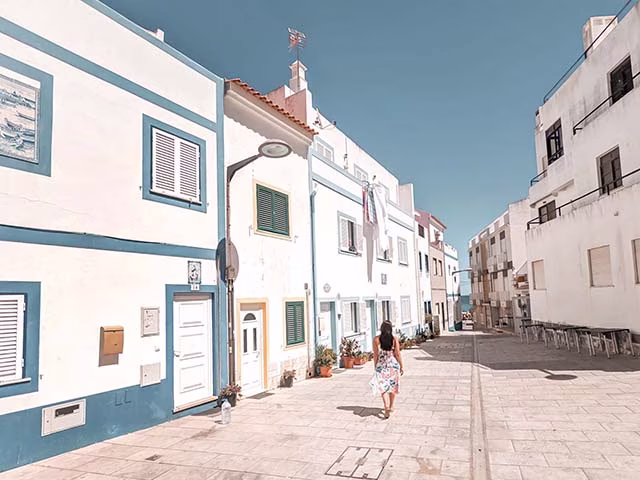 Girl walking among the beautiful blue buildings of the town Armação de Pêra in Faro Algarve Portugal, holiday destination family-friendly travel inspiration