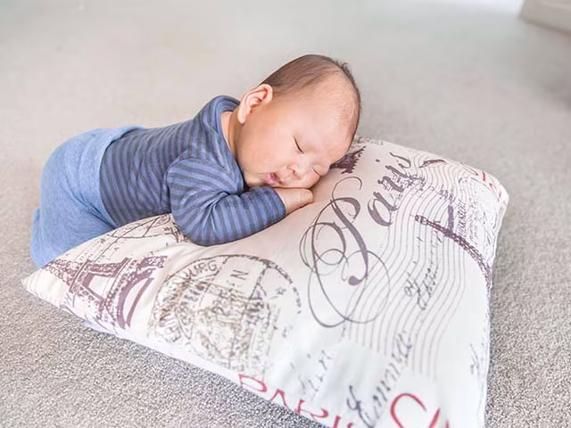 Cute baby sleeping on a vintage Paris patterned pillow