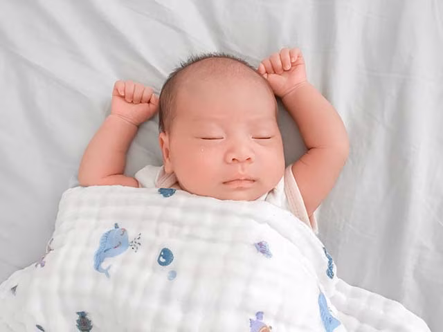 Baby sleeping with arms stretching, sleep training methods