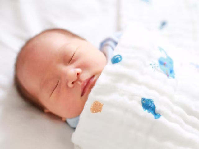 cute baby sleeping in muslin wrap