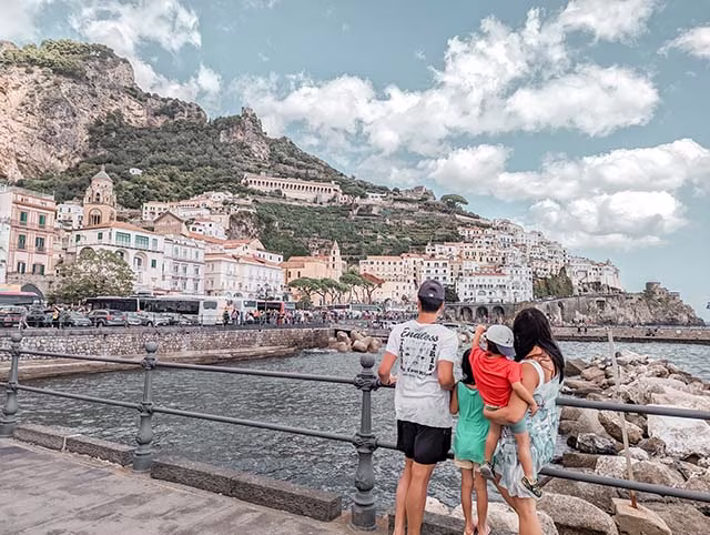 Family of 4 admiring the beautiful view of the colourful houses on the hilltops of Amalfi Coast in Italy