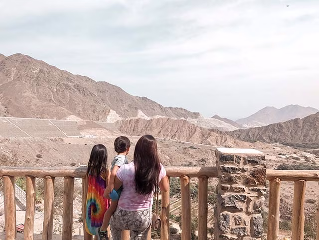 Millennial mum with two kids looking out to the rural scenery of Khor Fakkan, UAE