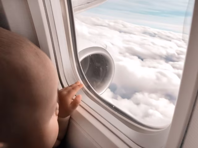 Baby looking out the window from the plane, above the cloud