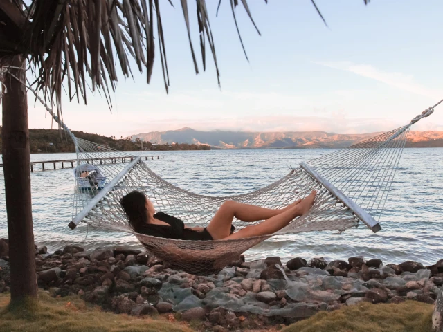 girl relaxing on a hammock under palm tree in Fiji island sunset silhouette family guide cover