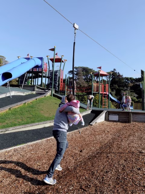 Father and toddler on flying fox at wellington botanic gardens playground on a beautiful clear day